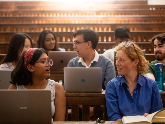 University of Cambridge students talking behind their computers during a lecture in the Student Services Centre old lecture hall.