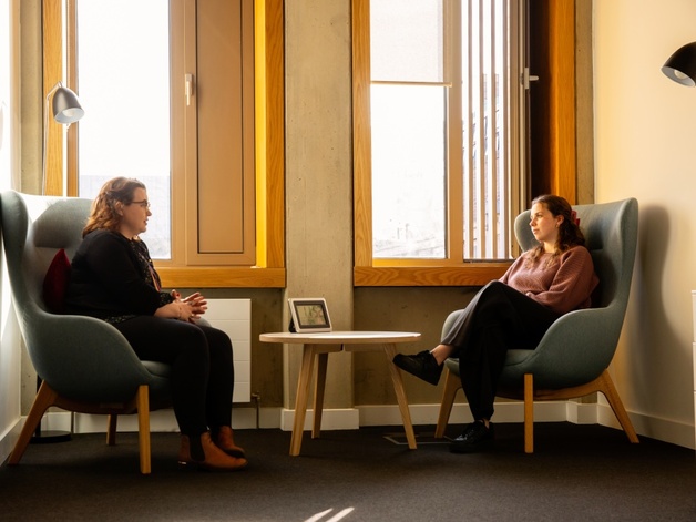A University Student Wellbeing Counsellor talking to a student while sitting in a cosy corner in front of a window at the Student Services Centre.
